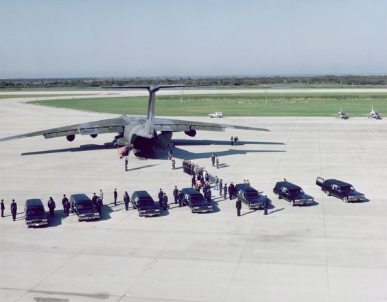 The Challenger crewmember remains are being transferred from 7 hearse vehicles to a MAC C-141 transport plane at the Kennedy Space Center's Shuttle Landing Facility for transport to Dover Air Force Base, Delaware. The STS-51L crew consisted of: Mission Specialist, Ellison S. Onizuka, Teacher in Space Participant Sharon Christa McAuliffe, Payload Specialist, Greg Jarvis and Mission Specialist, Judy Resnik. In the front row from left to right: Pilot Mike Smith, Commander, Dick Scobee and Mission Specialist, Ron McNair.